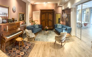 Vorraum der Location Wohnzimmer Fürth mit Holzboden, Couch, Klavier und Glastür zum Konferenzraum