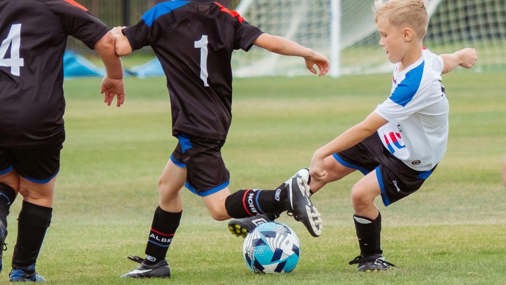 Fußballspiel mit drei Jungen aus inklusiven Teams in einem fairen Zweikampf.