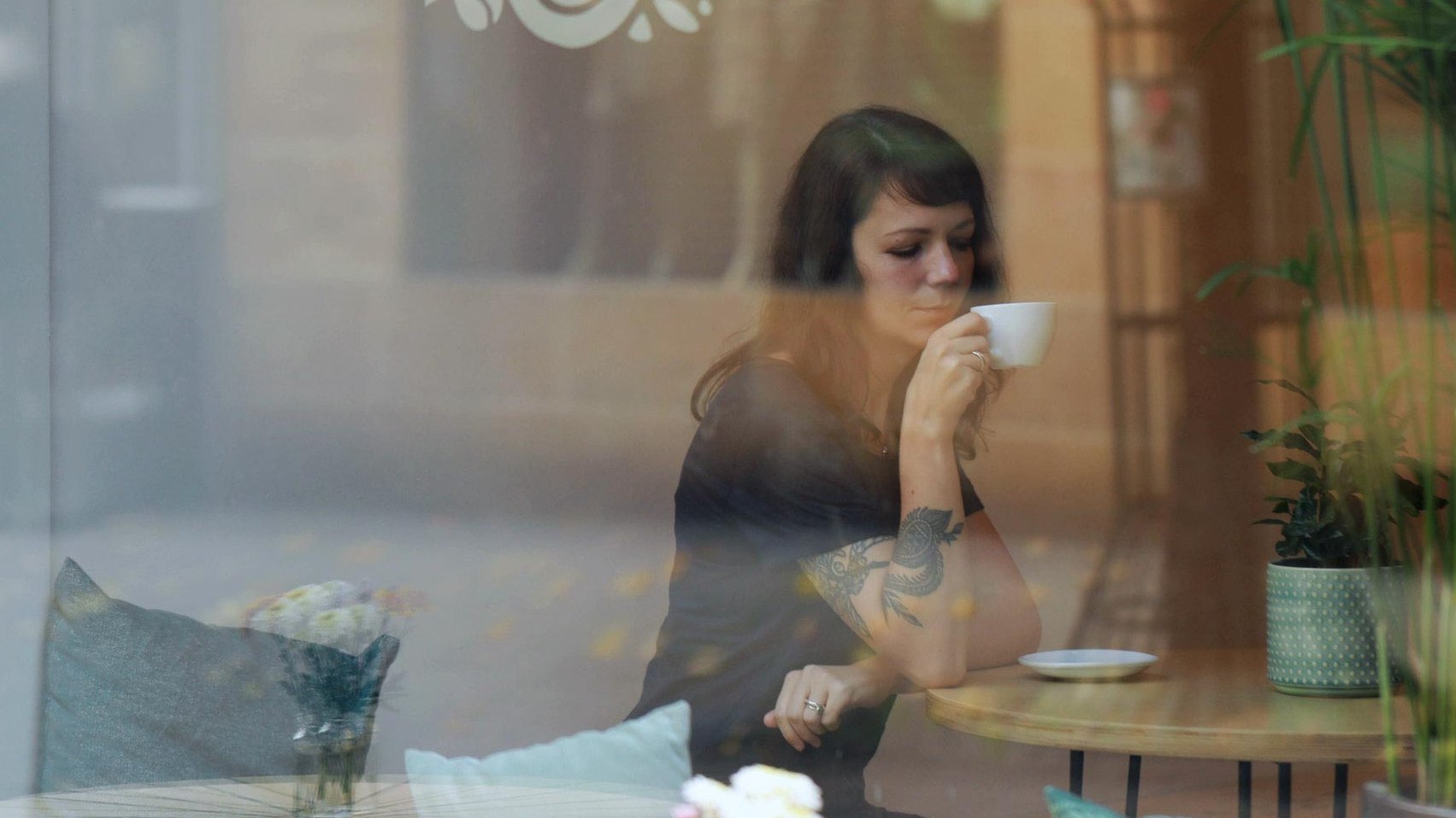 Eine junge Frau sitzt im Kaffeesuriums und genießt ihren Kaffee in Fürth. 