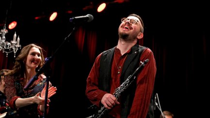 Ein fröhlicher Klarinettist spielt live, während eine Dame begeistert applaudiert bei Jewish Music Today.