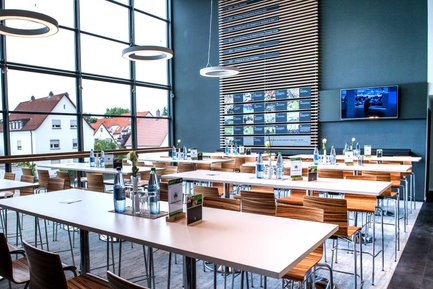 Große Fensterfront im Sportpark Ronhof mit Stühlen und Tischen, lichtdurchfluteter Veranstaltungsraum