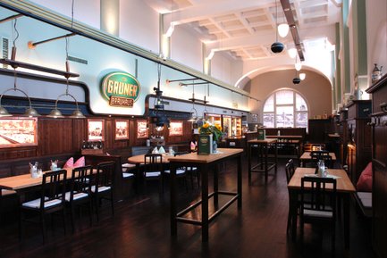 Gastraum im Grüner Brauhaus Fürth mit Bar, großem Logo sowie Holz und Stehtischen