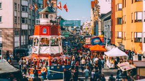 Der rot-weiße Backfischturm auf der Michaelis-Kirchweih mit vorbeigehenden Besuchern und Ständen.