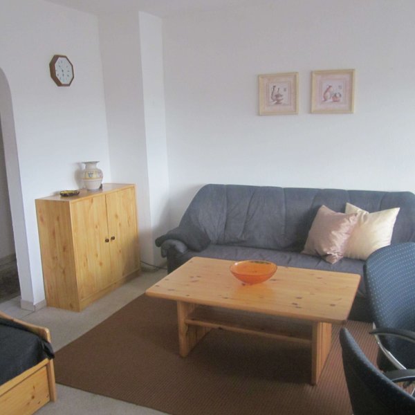 Wohnlicher Raum einer Ferienwohnung mit Couch, Beistelltisch sowie dekorativen Bildern und Vasen