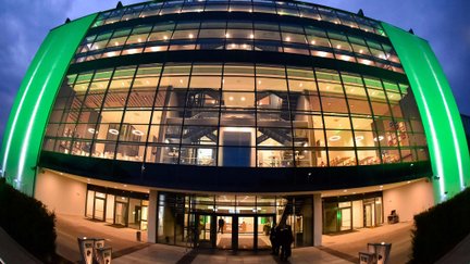 Modernes Außengebäude der Haupttribüne im Sportpark Ronhof | Thomas Sommer, grün beleuchtet mit großer Glasfassade