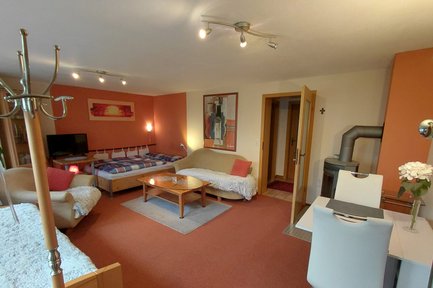 Wohnzimmer der Ferienwohnung Anita Pfeiffer im Landkreis Fürth mit gemütlicher Couch und orangefarbenem Stil
