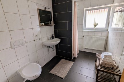 Modernes Badezimmer der Ferienwohnung Feld & Flair in Fürth mit weißen und anthrazitfarbenen Fliesen
