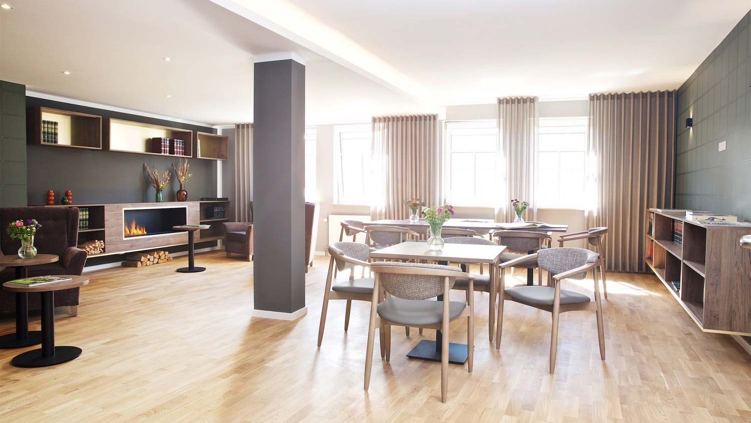 Heller, gemütlicher Raum in der Rosengarten Residenz mit Parkettboden, Tischen und Stühlen