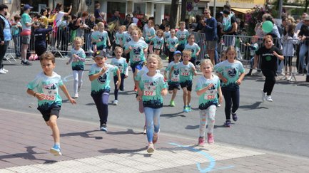 Kinder mit Startnummern laufen beim Metropol Kidsmarathon, während Eltern anfeuern