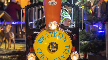 Kind schaut aus der kleinen fahrenden Lok auf dem Fürther Weihnachtsmarkt, fröhliche Szene.
