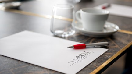Nahaufnahme eines Blocks mit Freiraum-Logo im Werners Boutique Hotel Fürth, Kaffeetasse und Glas im Hintergrund