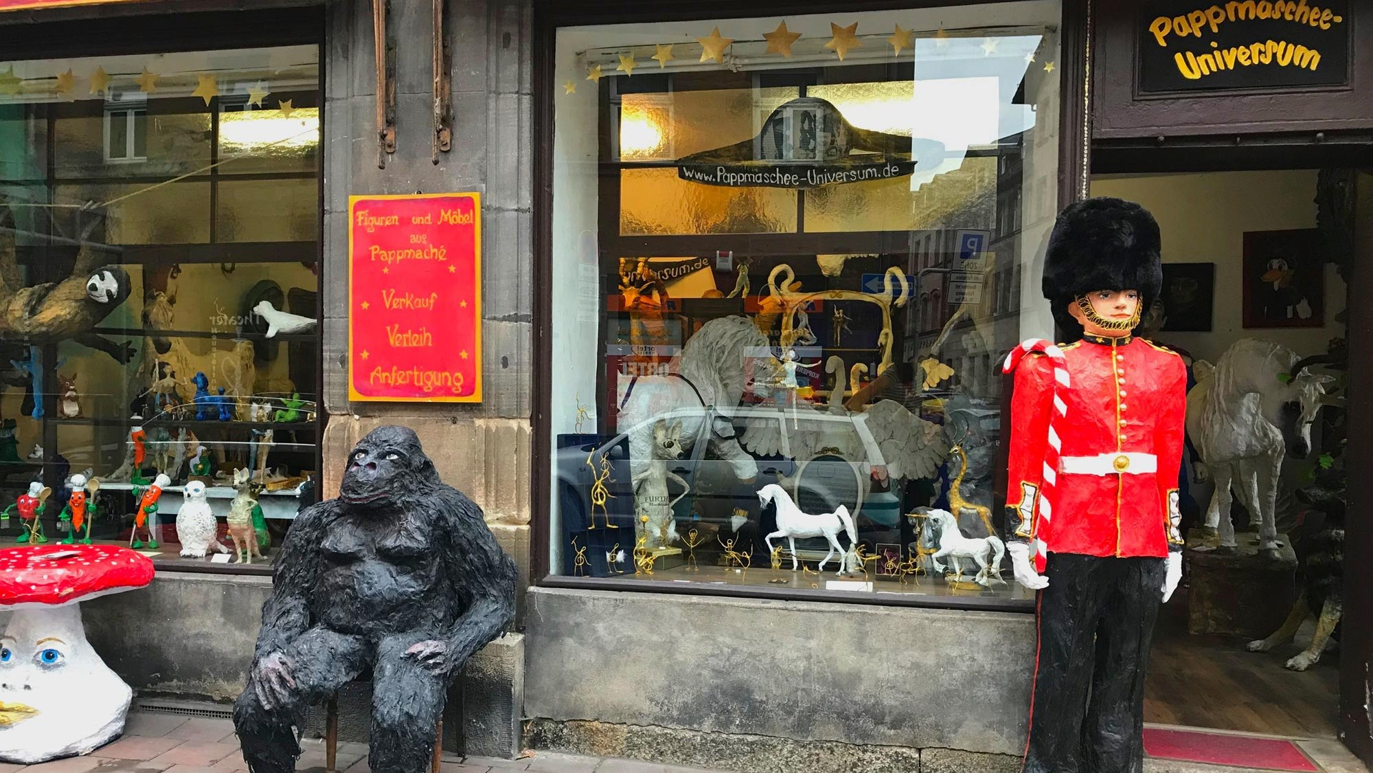 Zwei Pappmaschee-Figuren, ein Gorilla und eine königliche Wache, stehen vor dem Eingang zur Ausstellung.