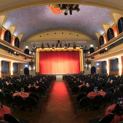 Der Saal der Comödie Fürth ist für die nächste Vorstellung bereit, die Bühne vom roten Vorhang verhüllt