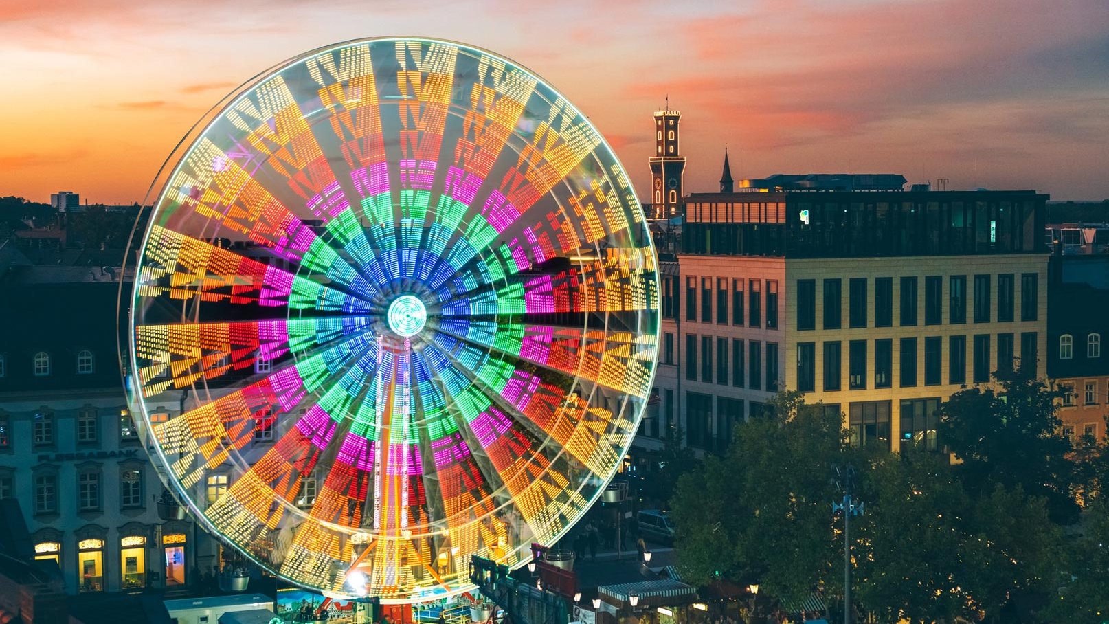 Panorama der Fürther Freiheit mit Riesenrad und Rathaus während der Michaelis-Kirchweih im Abendrot.
