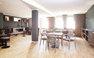 Heller, gemütlicher Raum in der Rosengarten Residenz mit Parkettboden, Tischen und Stühlen