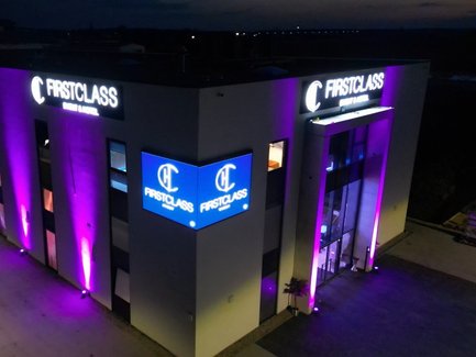 Außenansicht der Location First Class Event Fürth nachts mit lila Scheinwerfern und leuchtendem Logo