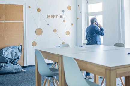 Person telefoniert in einem offenen, gemütlichen Büro und blickt aus dem Fenster