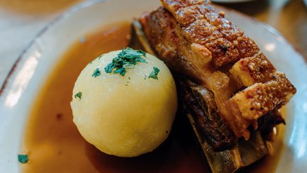 Schäuferle mit Kloß auf einem Teller in einem Restaurant in Fürth, eine traditionelle fränkische Spezialität.