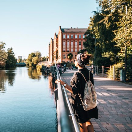 Junge Frau an der sonnigen Uferpromenade mit Blick auf die historischen kißkaltschen Häuser