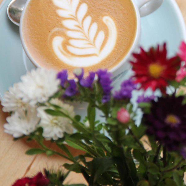 Eine Tasse Kaffee, ein Stück Kuchen und Blumen stehen dekorativ in einem Café in Fürth  3. Beschreibung (120–160 Zeichen)
