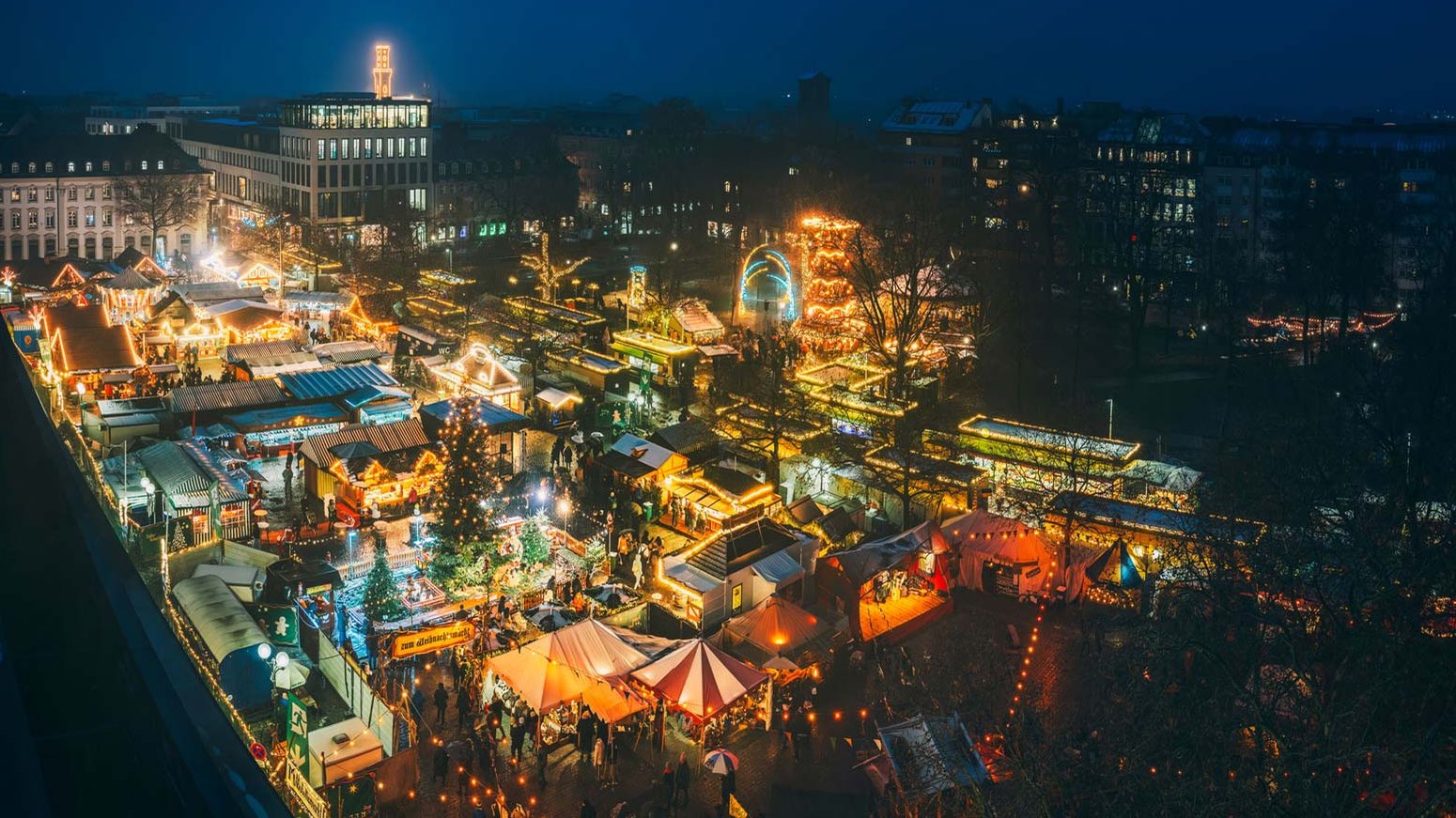 Weihnachtsmarkt auf der Fürther Freiheit mit vielen beleuchteten Buden und Besuchern, die durch die Gänge schlendern.
