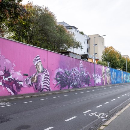 Buntes 250 Meter Graffiti am Grundigpark in Fürth mit Regenbogen-Hintergrund und Characters