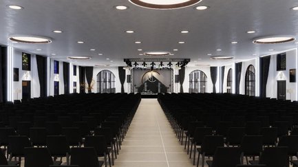 Große Halle im First Class Event Fürth mit schwarzen Stühlen in Reihen und Bühne vorne