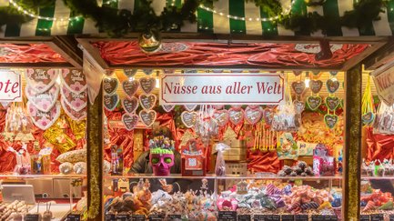 Süßwarenstand mit bunten Lebkuchenherzen sowie verschiedenen Nüssen und Süßwaren auf dem Weihnachtsmarkt.