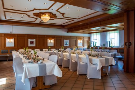 Innenraum im Landhotel Seerose mit festlich gedeckten Tischreihen, Holzwänden, Fließboden und Blumendeko
