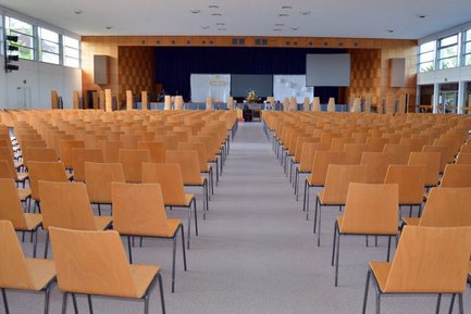 Große Halle im Gästehaus der Diakonie-Gemeinschaft Puschendorf mit Stuhlreihen, Durchgang und Bühne