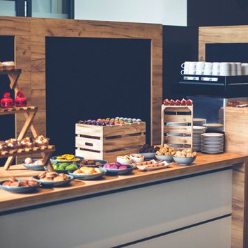 Nachspeisen schön angerichtet auf einem Holztisch mit danebenstehender Kaffeemaschine
