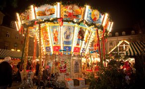 Beleuchtetes Kinderkarussell auf dem Weihnachtsmarkt der Fürther Freiheit mit Pferden und Kutsche.