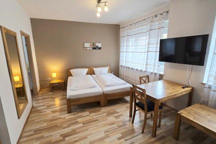 Ruhiger Schlafbereich mit TV und kleinem Tisch im Natalia Gästehaus in Fürth