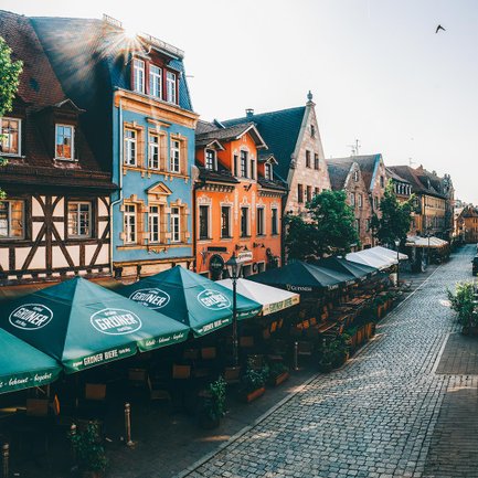 Morgenszene in der Gustavstraße mit Sonnenschirmen und gedeckten Plätzen vor den Restaurants