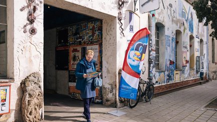 Frau liest Programmheft vor dem Eingang der Kofferfabrik, umgeben von Skulpturen und Gastspiel-Beachflag.