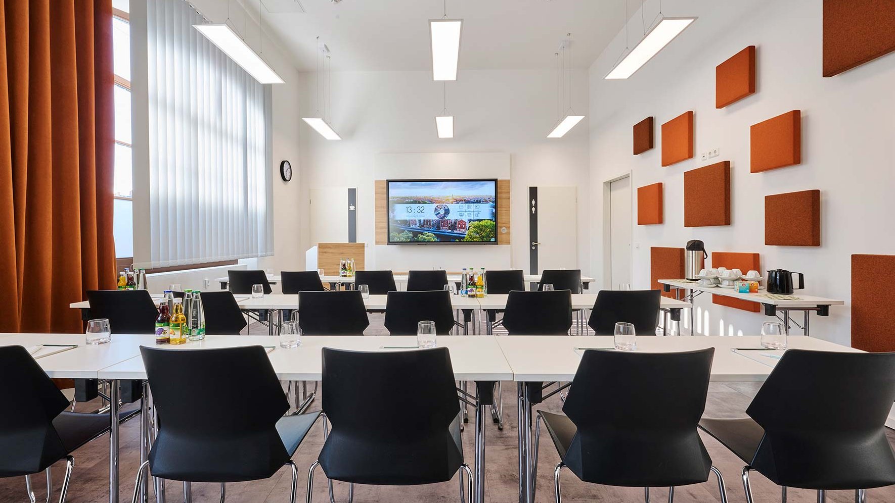 Heller Tagungsraum der Tourist-Information Fürth mit Stuhlreihen, Tischen, Bildschirm und Rednerpult