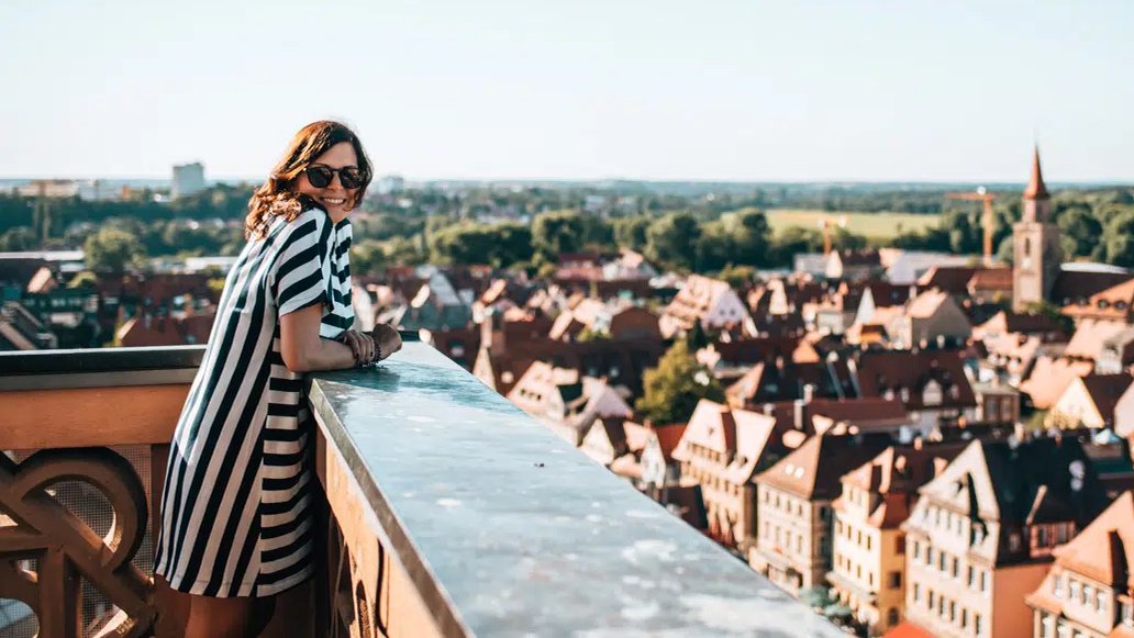 Eine junge Frau auf dem Rathausturm in Fürth genießt den Panoramablick über die Altstadt an einem warmen Sommertag