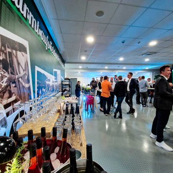 Menschen beim Netzwerken bei Wein und Catering, Polaroid-Druck mit Fußball-Highlights an der Wand