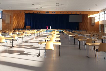 Blick von hinten auf die Halle der Diakonie-Gemeinschaft Puschendorf mit Tischen und Stühlen in Reihen