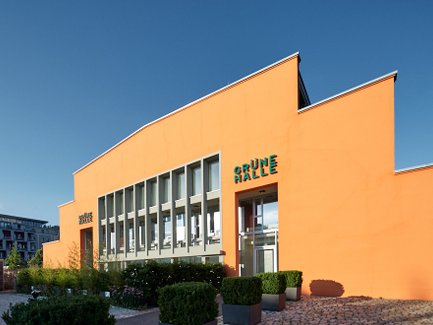 Markantes Gebäude Grüne Halle in der Fürther Südstadt mit stufiger orangefarbener Fassade und großer Fensterfront