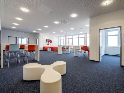 Großer Raum bei Neue Materialien Fürth mit Stehtischen, hohen Stühlen und hellem Tageslicht