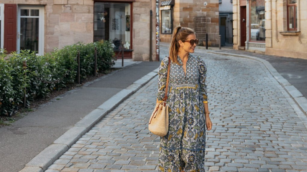 Junge Bloggerin läuft auf Pflasterstraße in Fürther Altstadt, Schieferhaus im Hintergrund sichtbar.