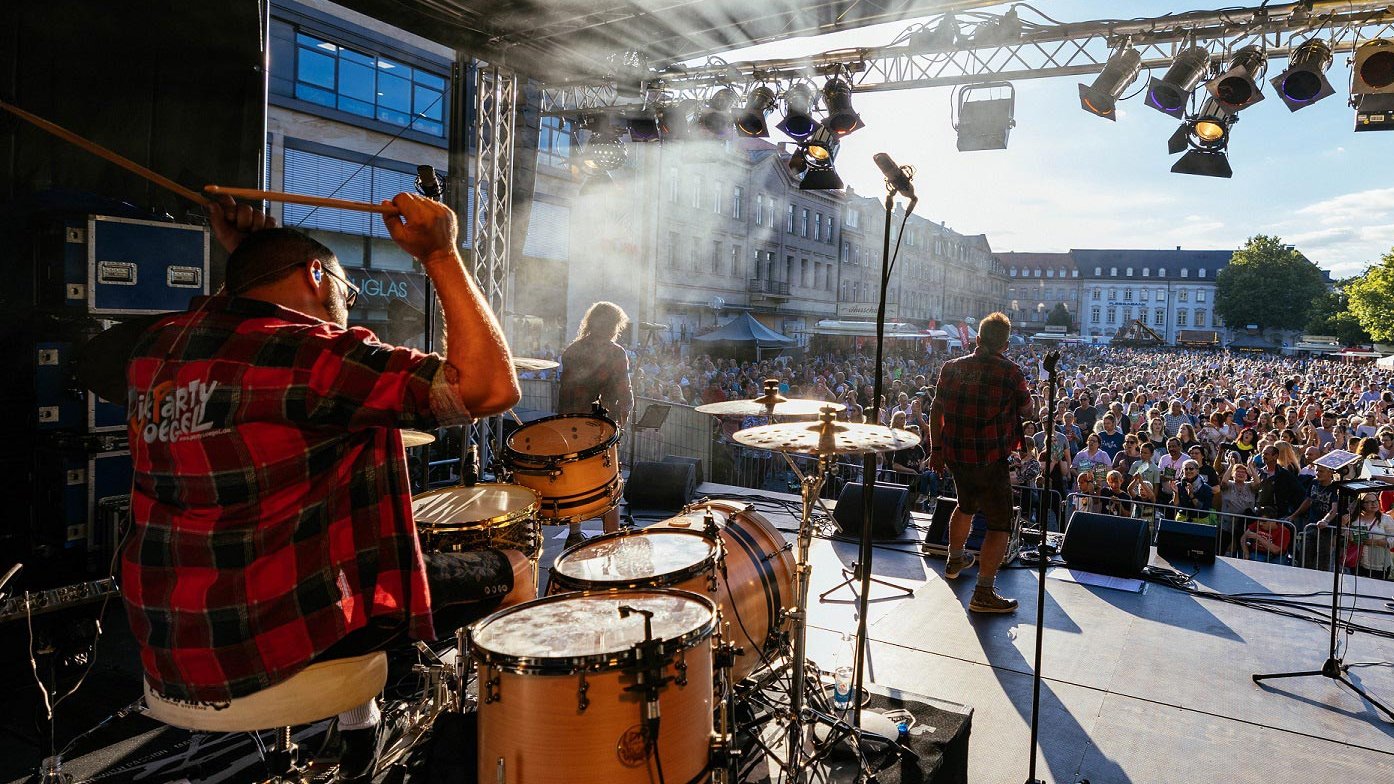 Blick von der Bühne auf das Publikum beim Fürth Festival, Band spielt mit Schlagzeug, Keyboard, Gitarre und Gesang