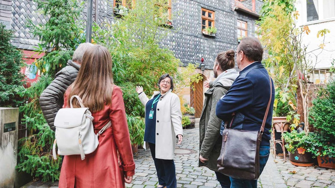 Teilnehmer einer Stadtführung stehen in der historischen Pfarrgasse in Fürth und hören aufmerksam der Stadtführerin zu