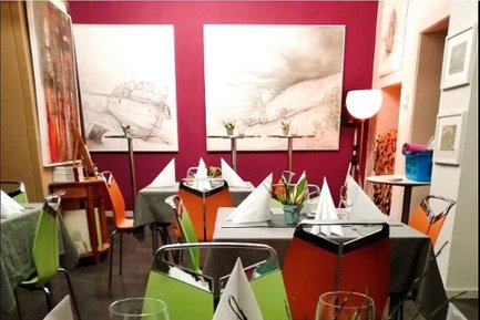 Gedeckte Tische im Katlscher Fürth mit bunten Stühlen, weißen Servietten und Kunst an den Wänden