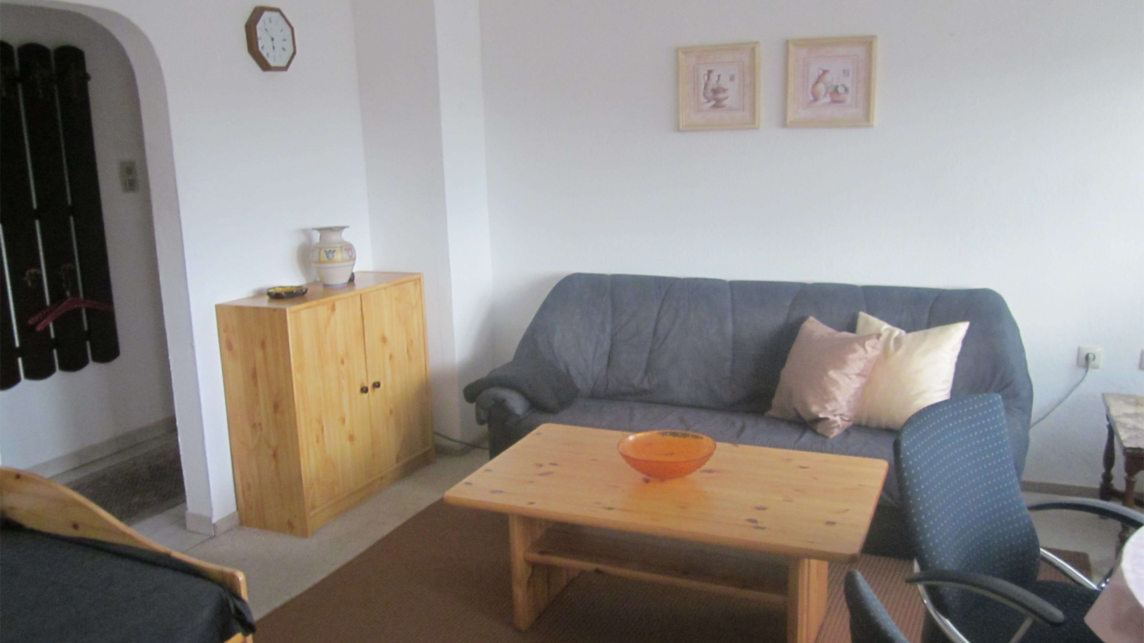 Wohnbereich einer Ferienwohnung mit Couch, Tisch sowie Bildern und Vasen als Dekoration