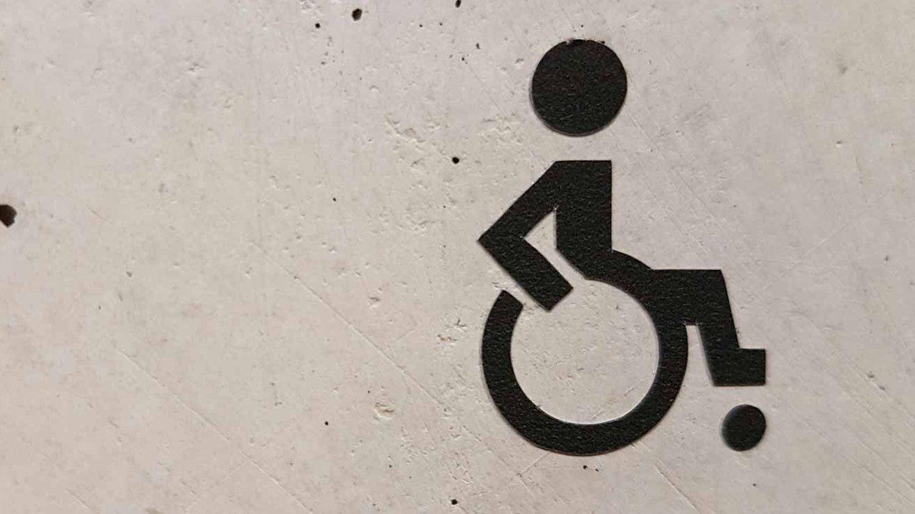 Rollstuhlfahrer-Symbol auf grauer Betonwand