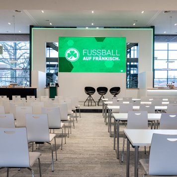 Professioneller Tagungsraum mit Teppichboden, Tischen, Stühlen und Leinwand für Präsentationen