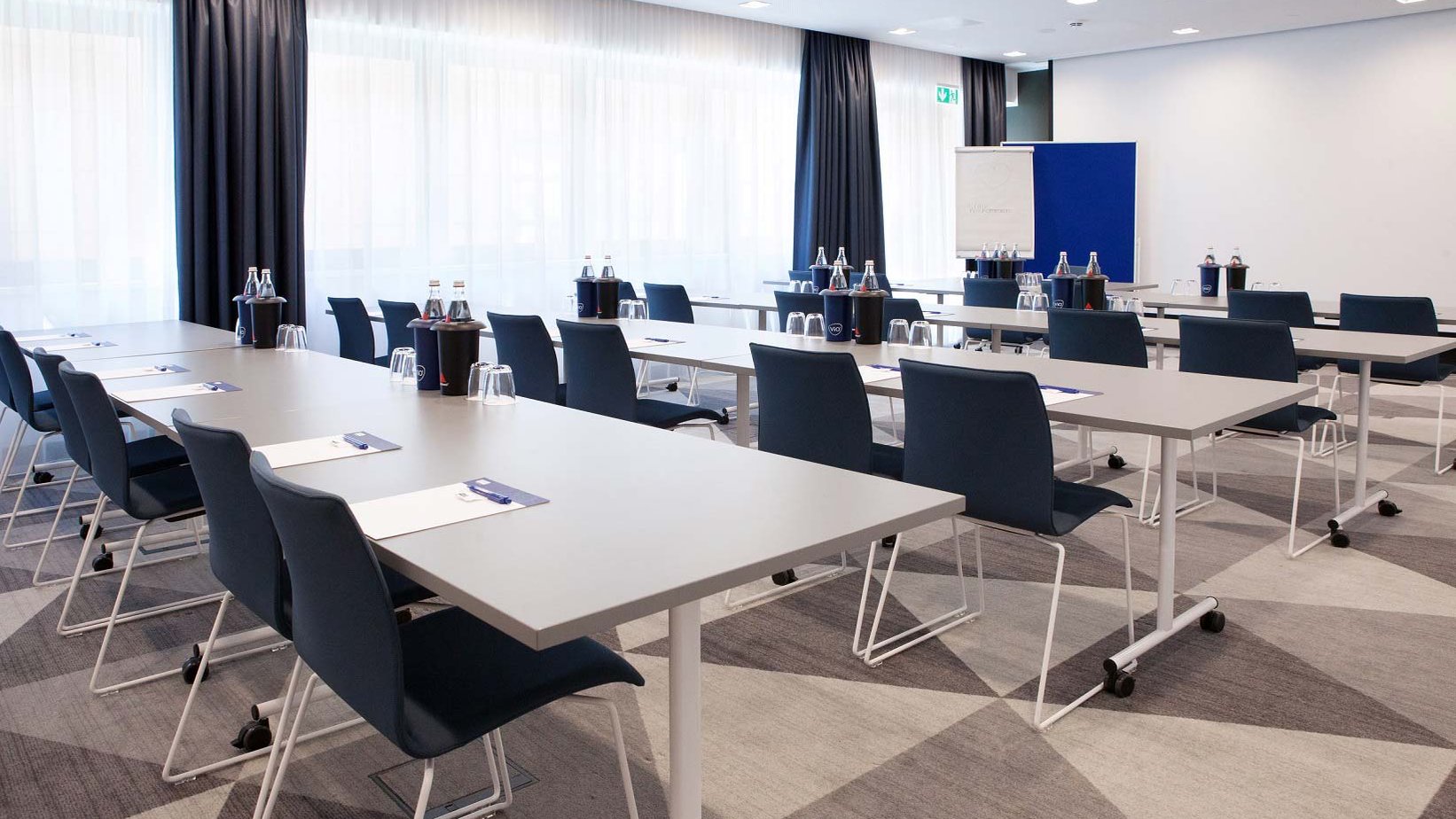 Moderner, klar strukturierter Tagungsraum im Holiday Inn Express mit Reihen aus Stühlen und Tischen