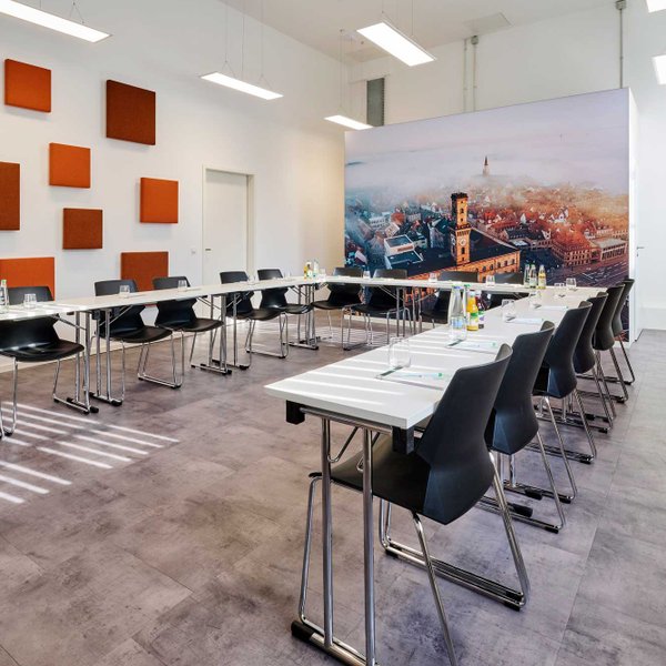 U-förmig bestuhlter Tagungsraum mit Tischen der Fürther Tourist-Information, Wandbild zeigt Rathaus